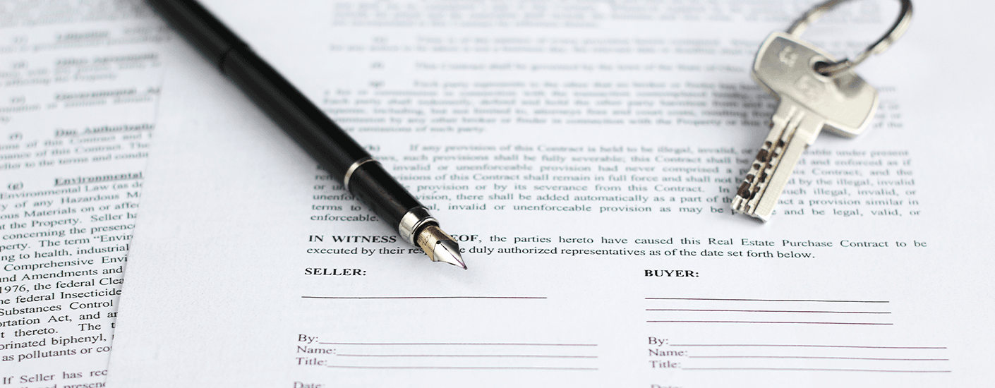 Home title document with signature lines, a pen, and house keys resting on the paperwork, symbolizing property ownership and real estate title transfer.